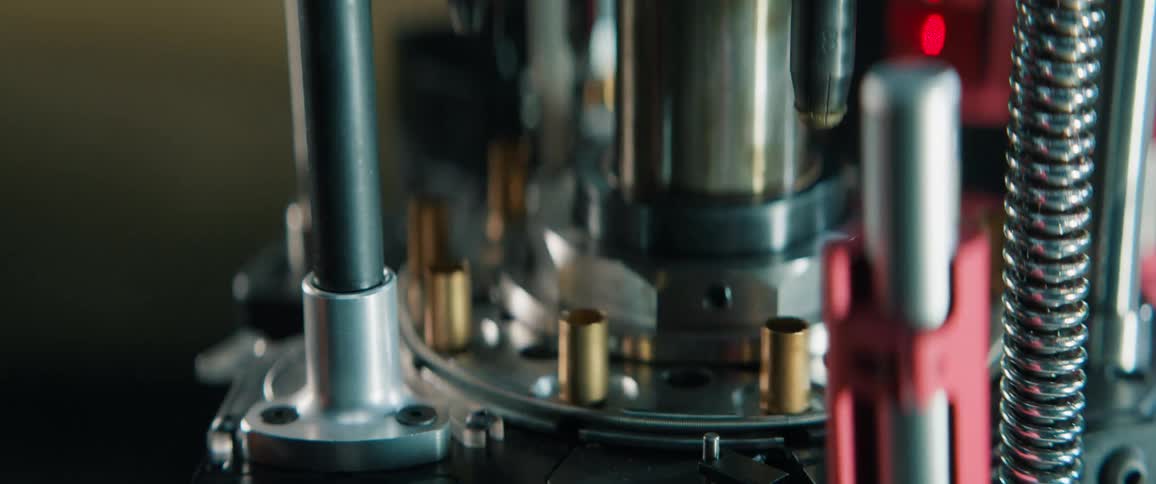 A close-up view of an automated reloading press meticulously processing empty brass bullet casings