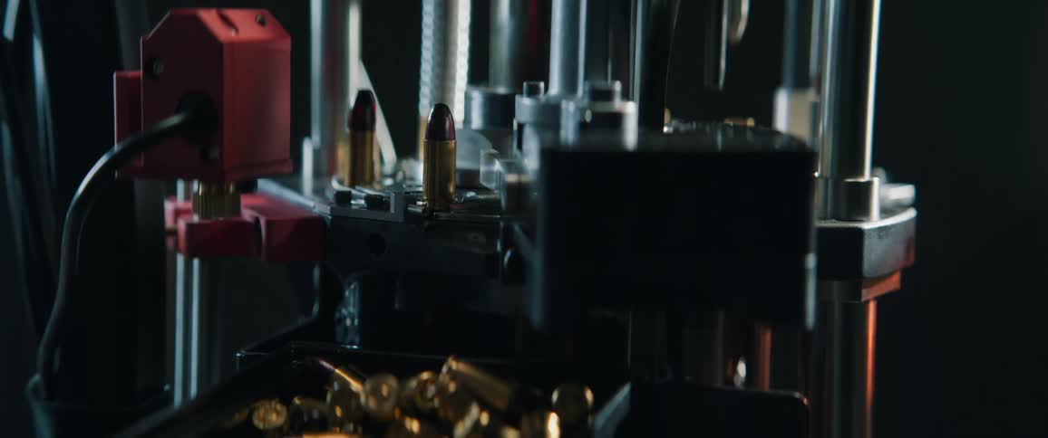 Close-up cinematic shot of an automated reloading press meticulously crafting bullets in a workshop