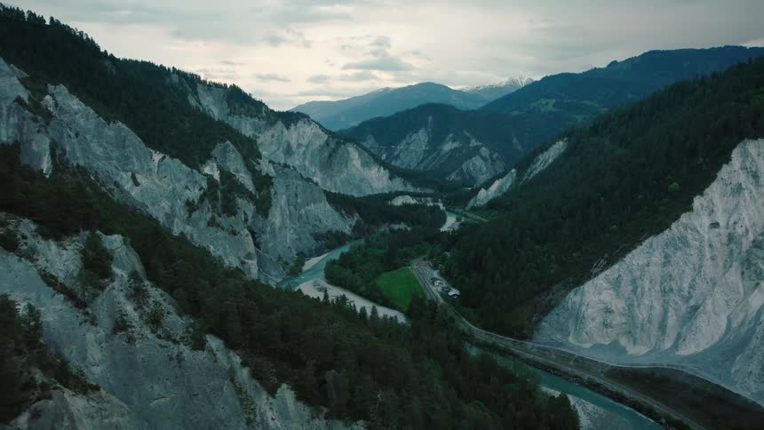 An epic aerial view of the moody and dramatic Rhine Gorge in Switzerland, where a river winds through a deep, forested canyon
