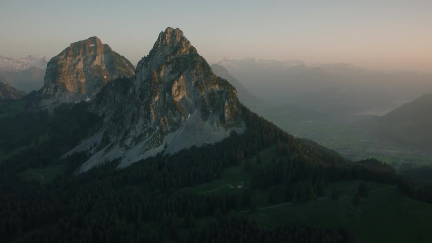 Epic aerial footage slowly pulls back from a towering mountain in the Swiss Alps during a beautiful sunset