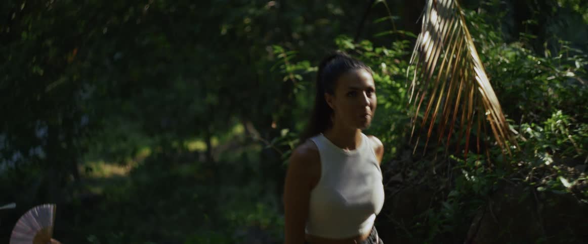 An athletic woman looks exhausted as she hikes through a lush, green forest in slow motion