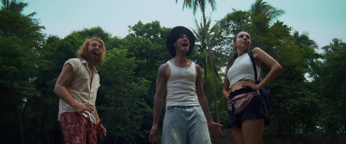 A low angle shot of three friends screaming in terror and running for their lives from an unseen danger in the jungle
