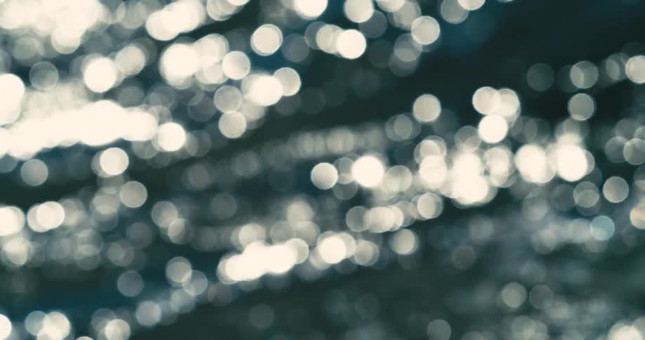 An abstract background of shimmering bokeh light reflecting on a dark water surface