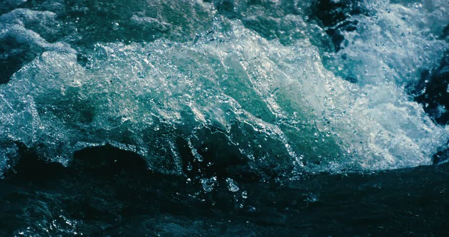 A powerful, churning wave of turquoise water is captured in mesmerizing super slow motion