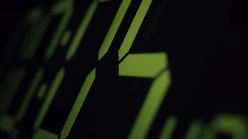 An extreme close-up of a green digital clock display blinking in the dark