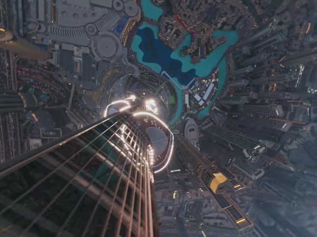 A mesmerizing top-down aerial shot slowly descends along the illuminated Burj Khalifa in Dubai at dusk
