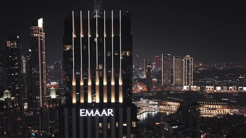 A stunning aerial view pans across the Emaar building to reveal the glittering Burj Khalifa and Dubai cityscape at night