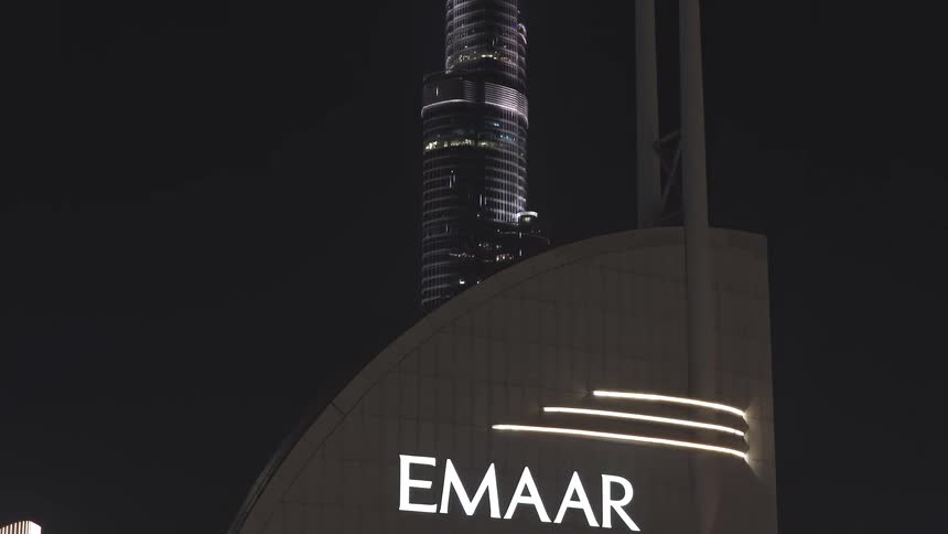 Stunning aerial shot reveals the iconic Burj Khalifa and glittering downtown Dubai skyline behind an Emaar building at night