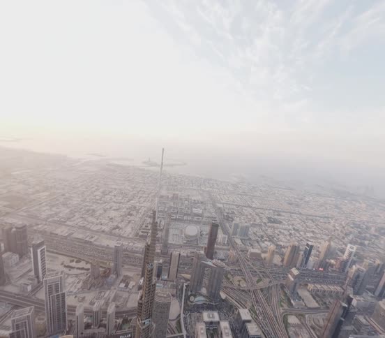 A breathtaking high-angle aerial view tilts down to reveal a top-down perspective of the iconic Burj Khalifa and the surrounding Dubai cityscape