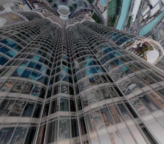 A dramatic aerial descent along the iconic Burj Khalifa's glass facade reveals the sprawling Dubai cityscape below