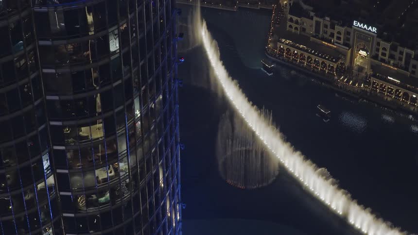 Stunning high-angle view of the illuminated Dubai Fountain performing its spectacular water and light show at night, next to the Burj Khalifa