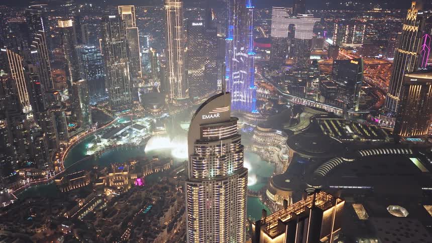 A spectacular aerial view of the glittering downtown Dubai cityscape at night, with the iconic Burj Khalifa and the Dubai Fountain at its center
