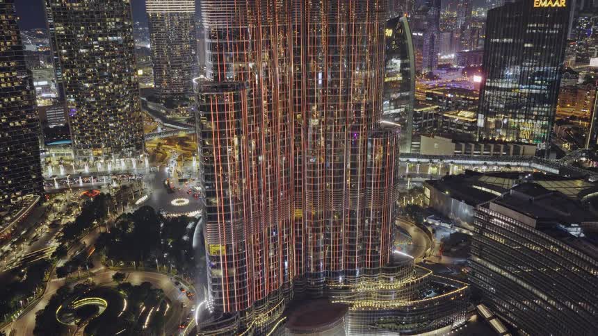 An incredible aerial view of the Burj Khalifa at night, with its dazzling light show illuminating the surrounding Dubai cityscape