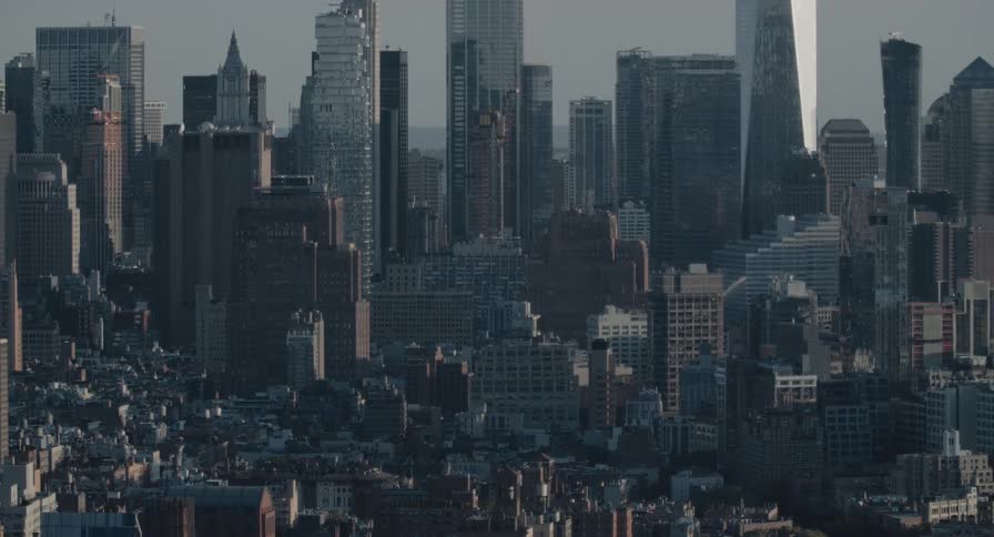 A vast, static view captures the densely packed skyscrapers of the New York City skyline under a hazy sky