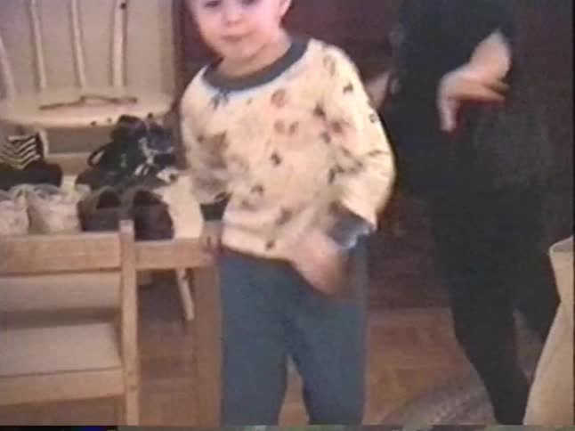 Vintage home video shows an adorable young boy in pajamas playing catch with a tennis ball inside his house