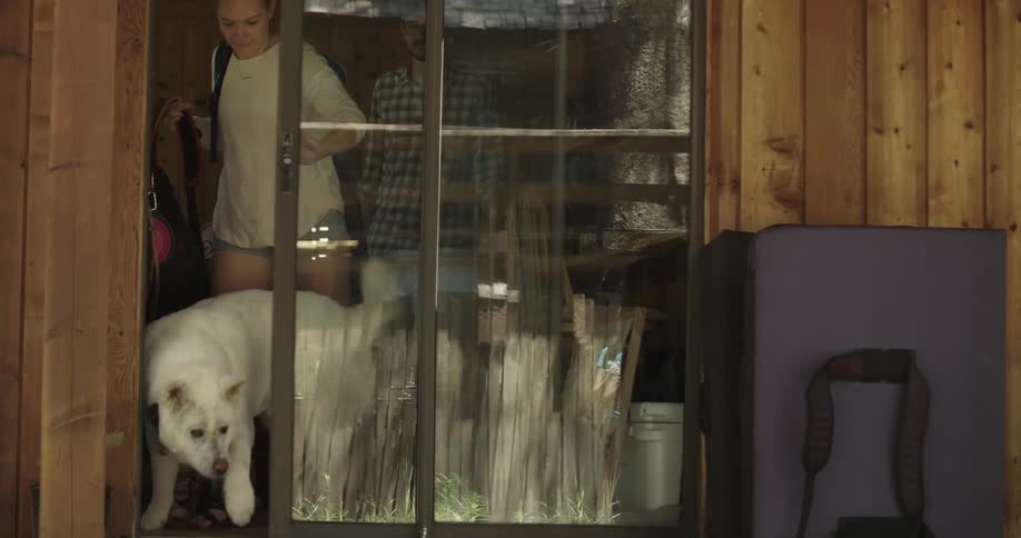 A couple follow their white dog outside