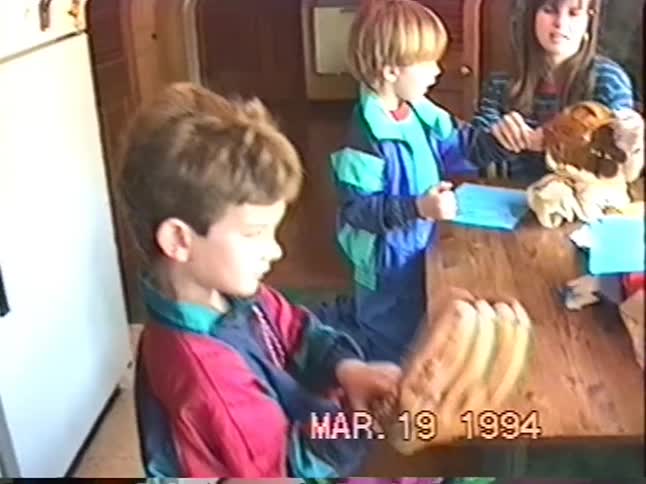 A nostalgic home video from 1994 shows two young boys excitedly opening presents and receiving new baseball gloves at a birthday party