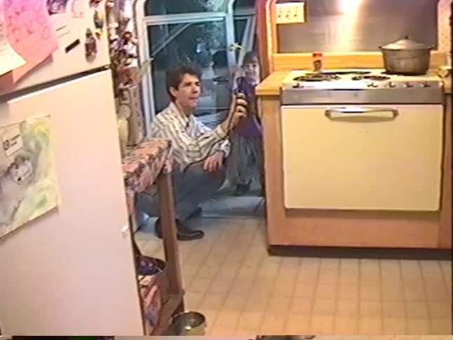 A father and his young son catch a mouse on a string in their kitchen in this vintage home video from 1994