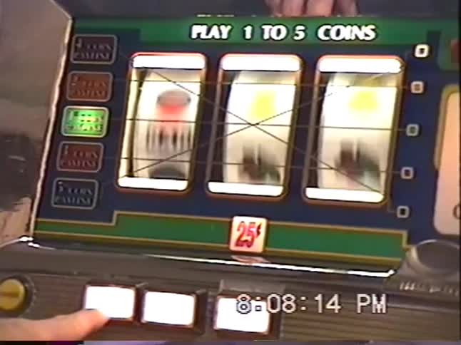 Vintage VHS footage shows a close-up of a person playing a classic spinning reel slot machine in a casino