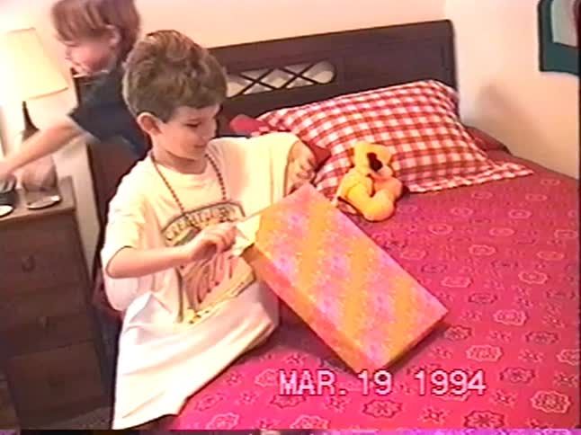 Two young brothers excitedly unwrap presents on their beds in this vintage home movie from 1994