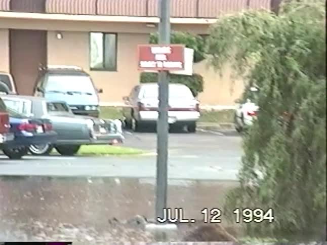 Vintage 1994 VHS footage of two children happily splashing and playing in a flooded apartment complex parking lot