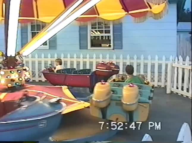 Nostalgic VHS footage from the 1990s shows young boys enjoying a colorful spinning boat ride at an amusement park