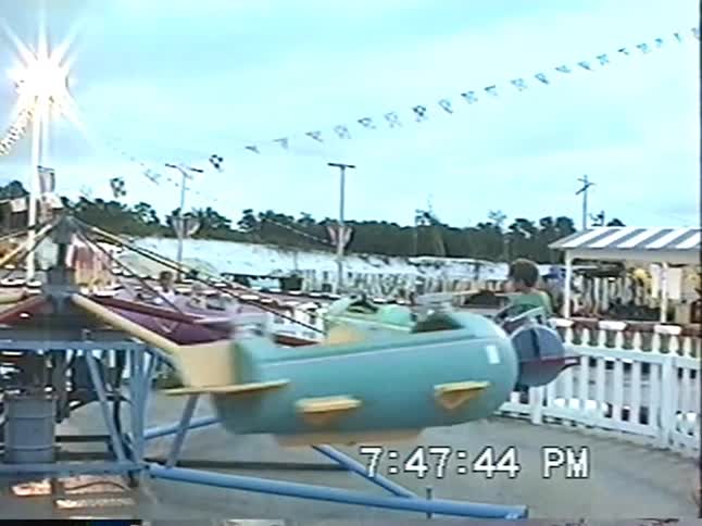 Smiling children have a blast on a colorful spinning spaceship and boat ride at an old-fashioned amusement park