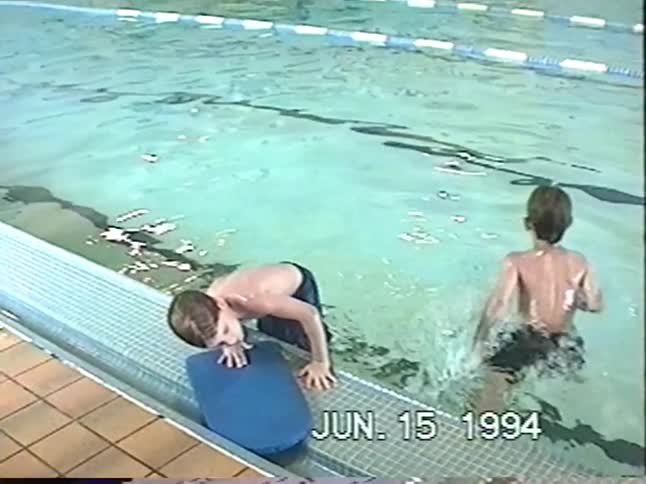 Vintage 1994 home video shows young boys in a swimming pool, with one resting on the side before swimming away