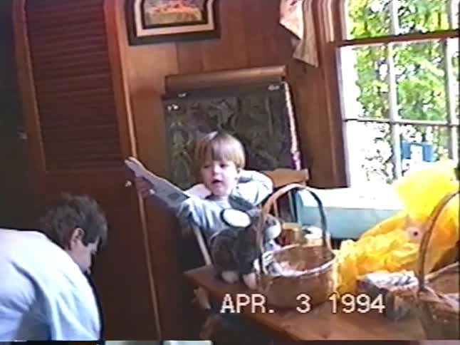 A young boy excitedly explores his Easter baskets filled with candy and toys in a nostalgic 1994 home video