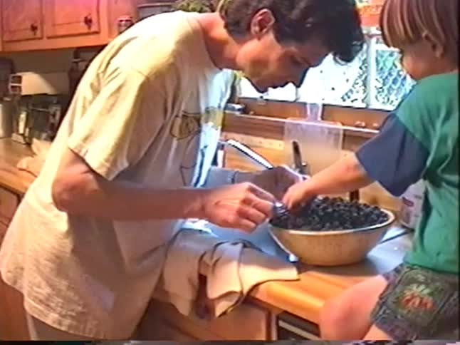 Vintage VHS footage from 1994 shows a father and son eating fresh blackberries together in their cozy home kitchen