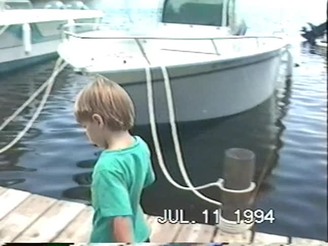 A father and his two young sons enjoy a summer day fishing with nets off a wooden dock in 1994