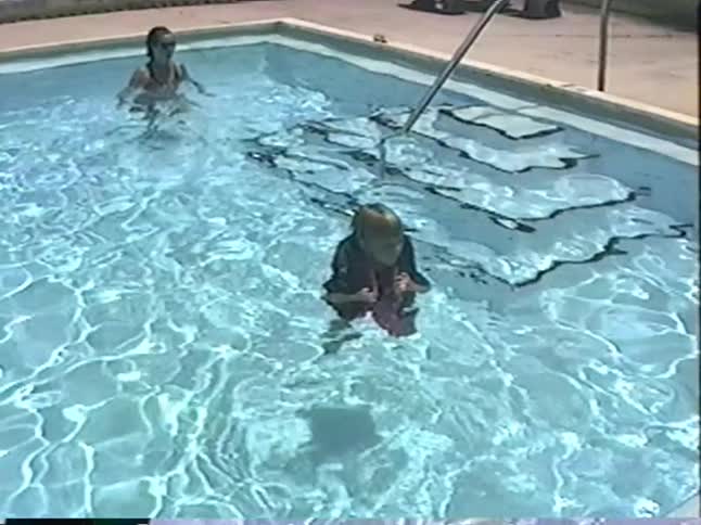Vintage home movie captures a young girl in a life vest bravely jumping into the pool to her waiting mother