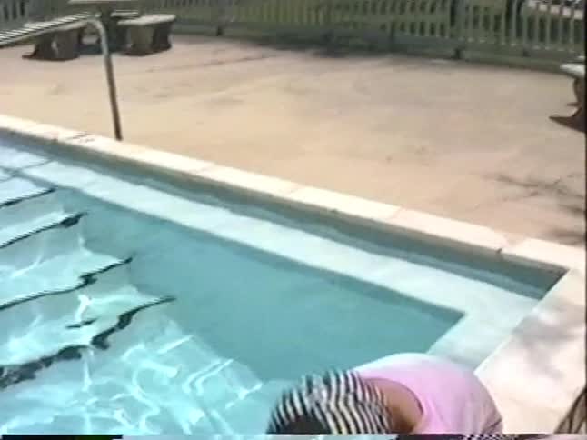 A vintage home video shows a little girl in a life jacket learning to swim with her mom, while her brother plays by the pool