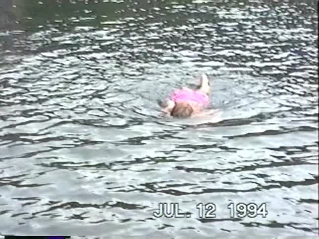 A woman and her children swim and play in a flooded parking lot in this vintage 1994 VHS footage