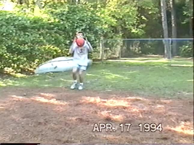 Vintage VHS footage from 1994 shows a young man with a mullet showcasing his basketball skills and trick shots in the backyard