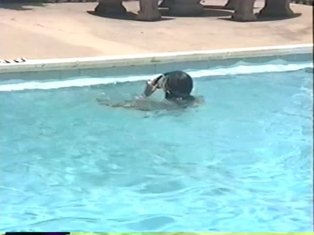 A woman swims freestyle in an outdoor pool before switching to a relaxing backstroke