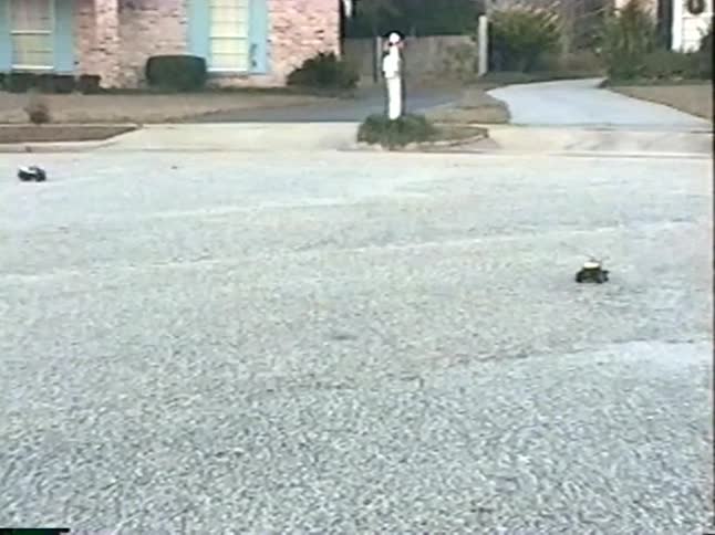 A nostalgic home video from the 90s shows a father and his young sons racing remote control cars in their suburban cul-de-sac