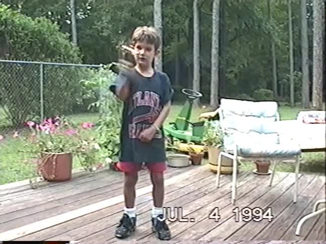 Vintage VHS footage from July 4th, 1994 shows a dad giving his sons a ride in a wagon pulled by a lawnmower, followed by the boys playing with sparklers
