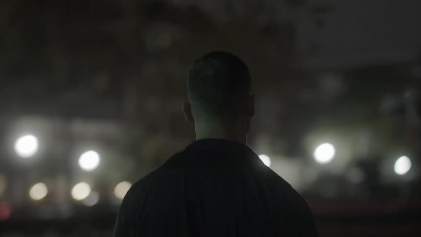 A man walks outside in a city at night