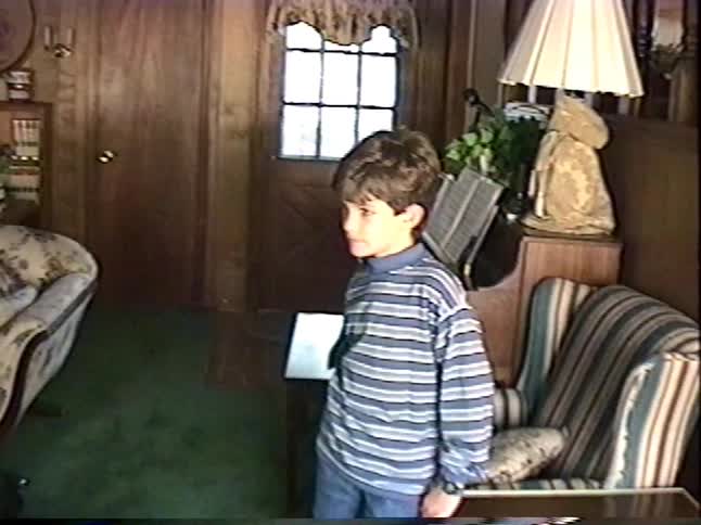 A young boy energetically runs in circles around the living room in a vintage home video