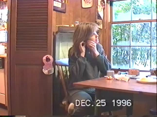 A young boy proudly shows off his Christmas gift from Santa while his mother tries on her new earrings in a heartwarming home video from 1996