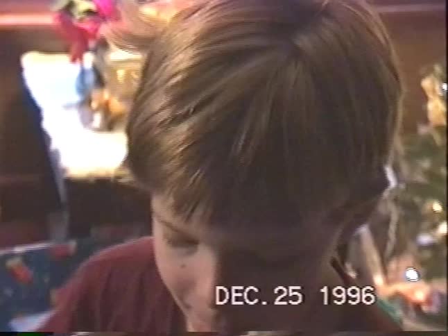 Vintage VHS footage from Christmas 1996 shows an excited young boy smiling and giving a present to the camera