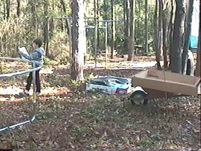 Vintage home video shows a father and son assembling a trampoline in a wooded backyard