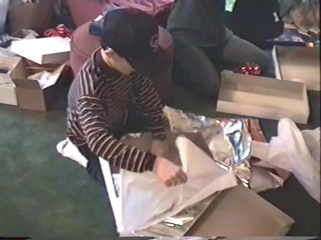 Vintage VHS footage captures a family excitedly opening presents together by the Christmas tree