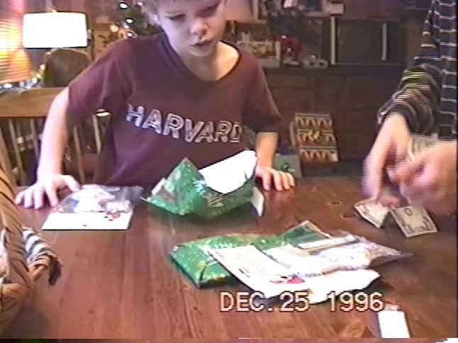 A vintage home movie from 1996 shows two excited young boys opening gifts and counting money on Christmas morning