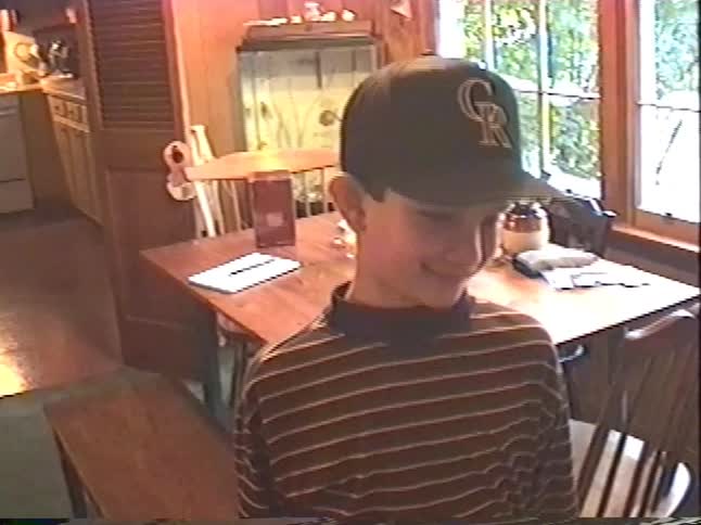 Vintage home video shows a young boy happily receiving a new baseball cap for Christmas