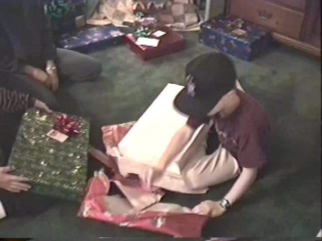 A family gathers around the Christmas tree as children excitedly unwrap their presents on Christmas morning