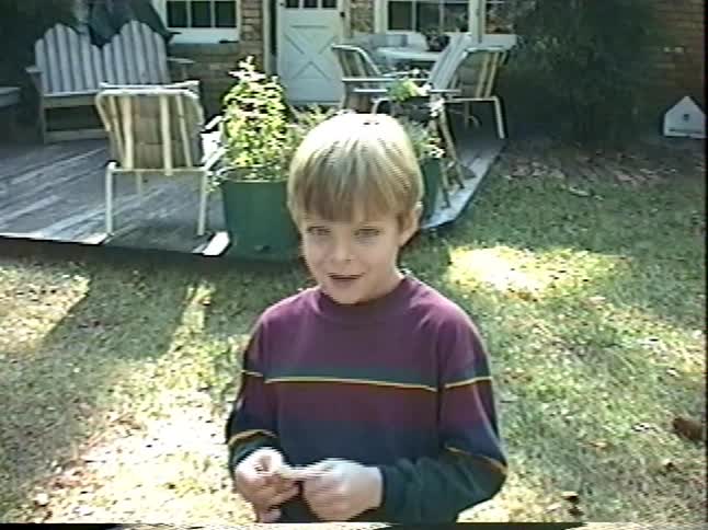 A young boy performs a simple magic trick for his friend in the backyard of their home
