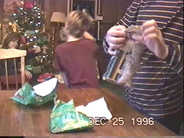 A nostalgic home video from 1996 captures children opening presents on Christmas morning in their cozy living room