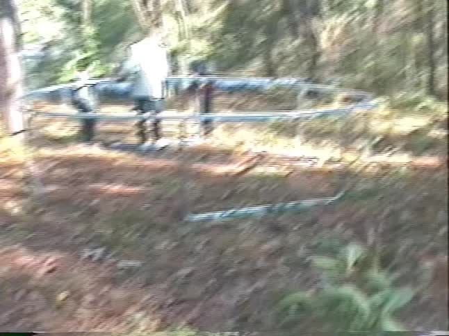 Vintage VHS footage shows a family with two kids assembling a new trampoline together in their wooded backyard